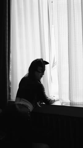 vertical video. Young woman wearing a cat mask by the window. costumes for erotic games. feminine attractiveness.