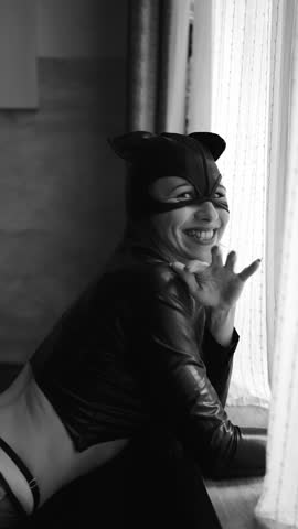 vertical video. Young woman wearing a cat mask by the window. costumes for erotic games. feminine attractiveness.