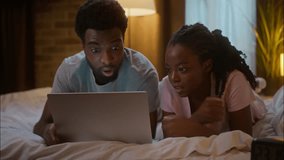 Worried upset frustrated African American ethnic couple family boyfriend girlfriend lying on bed laptop watching sport game online match failure losing frustration team lost at home bedroom together - Powered by Shutterstock - Get 15% off with code: PIKWIZARD15