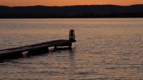 A wooden bridge on the shore of a lake at dusk at sunset and a burning kerosene lantern. A boat dock in the countryside. - Powered by Shutterstock - Get 15% off with code: PIKWIZARD15