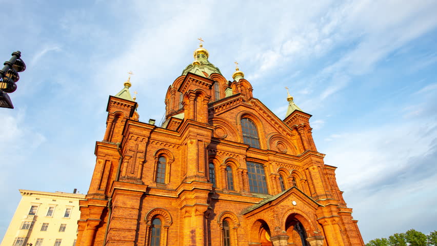 Uspenski cathedral in Helsinki Finland hyper lapse - time lapse of Christian Orthodox religion church made of red brick showcasing magnificent architecture. Historical temple in setting sun light.