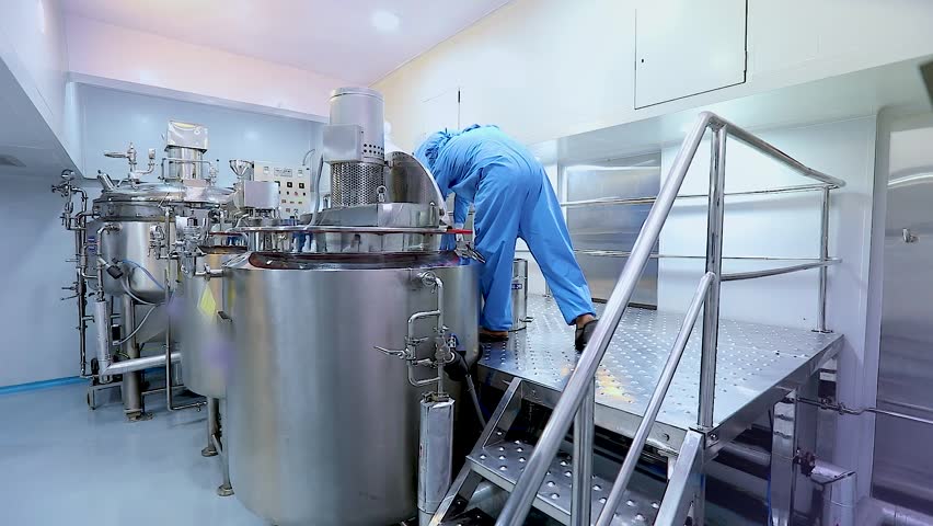pharmaceutical workers in industrial stainless steel vessels in cosmetic manufacturing factory for cream, lotion, gel, or liquid production with automated mixing, batching, and processing equipment.