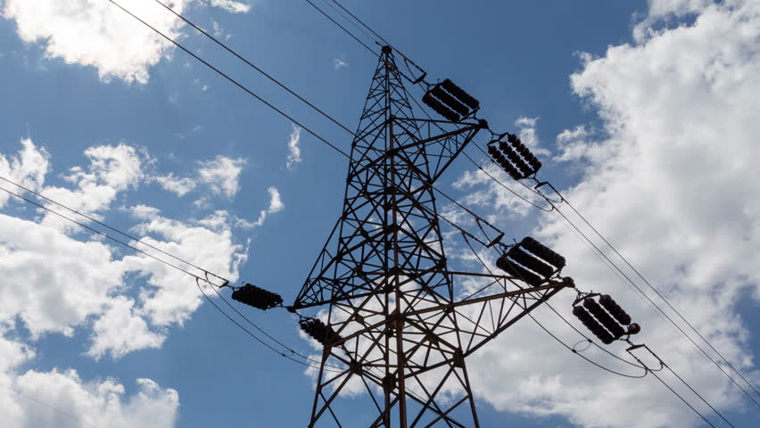 Transmission tower supporting an overhead high voltage power line - dramatic time lapse. The pylon carries wires that transport electric power from generating stations to electrical substations.