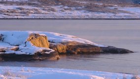 Drone footage shows rocky coastal cliffs in Larvik, Norway, partially snow-covered and glowing in sunrise or sunset light during winter season. - Powered by Shutterstock - Get 15% off with code: PIKWIZARD15
