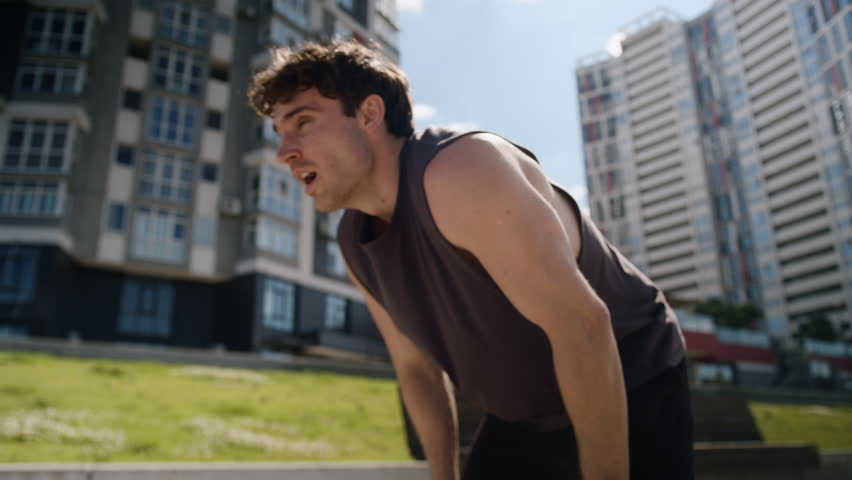 Exhausted Caucasian European young man tired guy male athlete outdoors sportsman break jog running sport training workout hard breath sweaty stop relax sportive activity lifestyle runner city street