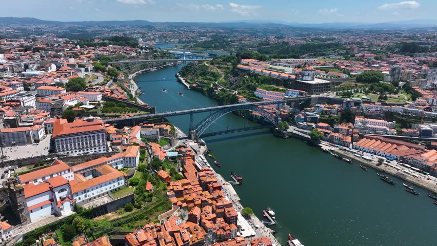 Aerial video of Dom Luís I Bridge and Monastery of Serra do Pilar over the Douro River in Porto, Portugal, surrounded by cityscape and hills