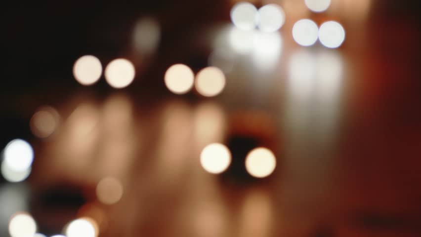 Defocused headlights of moving traffic at night on city road at rush hour.
