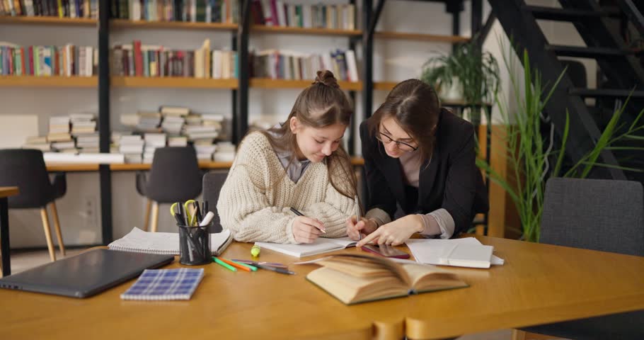 In a bright and inviting library, schoolgirl engage with their teacher, exploring lessons through collaboration and hands-on learning. It