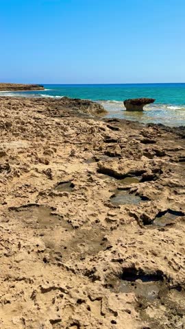 Picturesque beach, waves crashing on the sandy shore. Sea waves beat against the rocks. Cyprus Island, Mediterranean Sea.