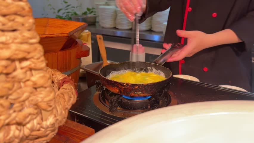 cook stirs egg making omelette scrabble egg Breaking Egg On Frying Pan. Egg falling on hot frying pan in slow motion.