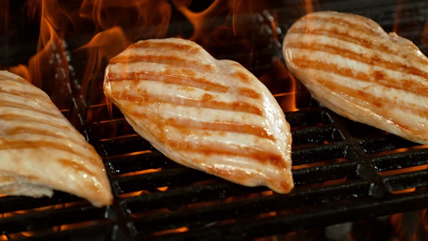 Super Slow Motion of Delicious Chicken Breast Fillets on a Grill with Roaring Flames
