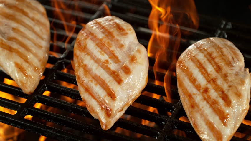 Super Slow Motion of Delicious Chicken Breast Fillets on a Grill with Roaring Flames