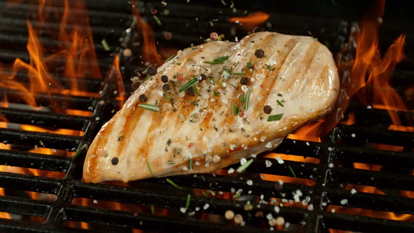 Super Slow Motion of Delicious Chicken Breast Fillets on a Grill with Roaring Flames