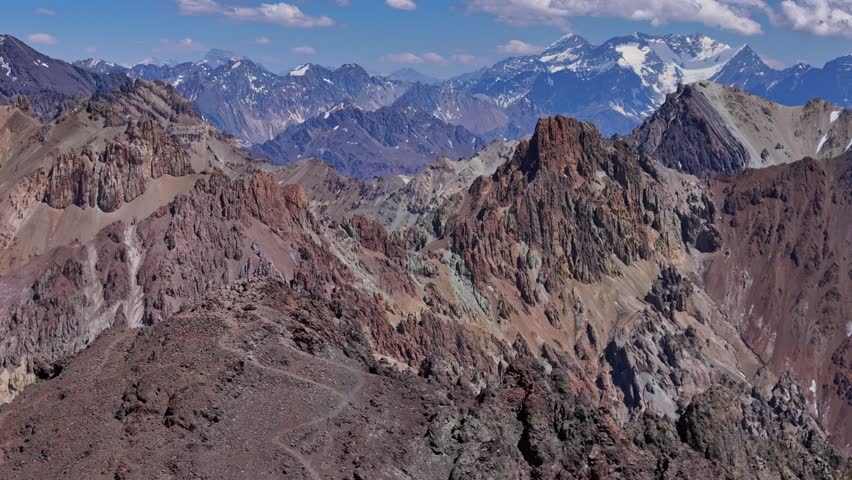 Dramatic peaks and deep valleys in the Andes near Aconcagua. The aerial view captures steep rocky slopes and glacier-covered summits.