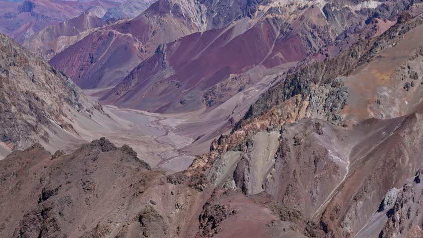 Dramatic peaks and deep valleys in the high Andes mountain range. Jagged ridges and eroded slopes define this extreme environment.