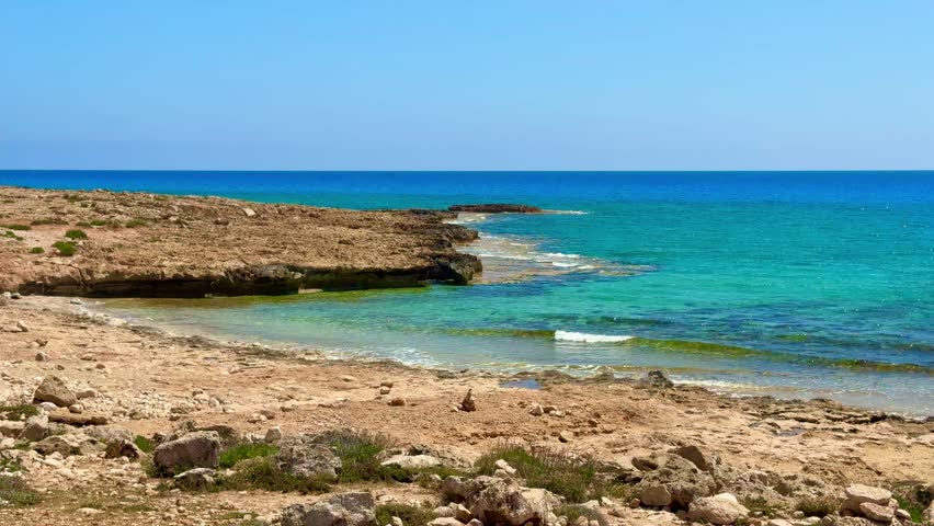 Picturesque beach, waves crashing on the sandy shore. Sea waves beat against the rocks. Cyprus Island, Mediterranean Sea.