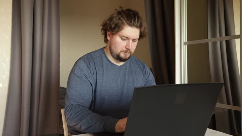 Man with laptop at home feels disgusted, navigating an online job, sitting in a cozy home office. - Powered by Shutterstock - Get 15% off with code: PIKWIZARD15