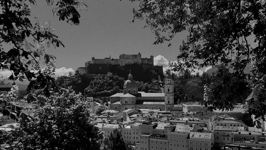 Vintage film-stylised black and white Video of Salzburg city in Austria. Castle with the mountains in the background.