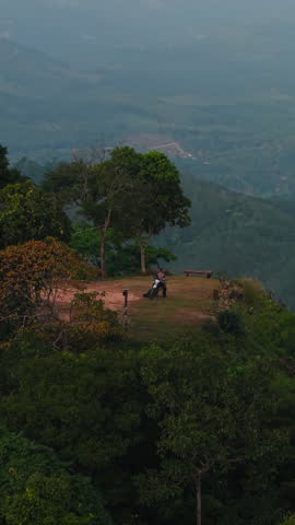 Lone biker on top of a mountain full of forests and lots of vegetation from a drone view