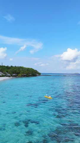 woman in a bikini relaxes on a yellow kayak floating on clear turquoise sea, top-down view from above, peaceful moment in tropical paradise, summer holiday, maldives, travel, holidays, vacation