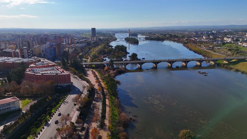 Aerial view of Guadiana river with modern arched bridge, riverside roads and islands in Badajoz Spain