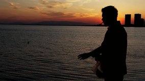 Man Silhouette Feeding Throwing Bread to the Fishes in Sunset Light - Powered by Shutterstock - Get 15% off with code: PIKWIZARD15