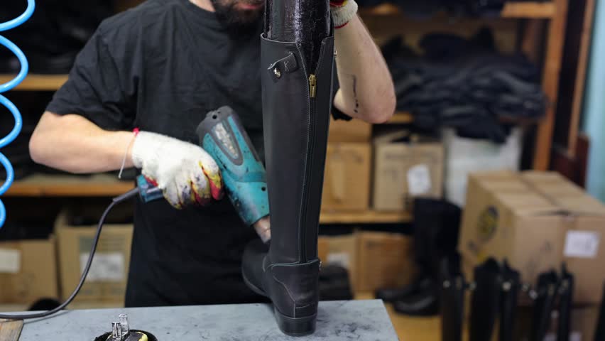 Shoemaker warms up the skin when making boots. A shoemaker works in his workshop at a shoe factory