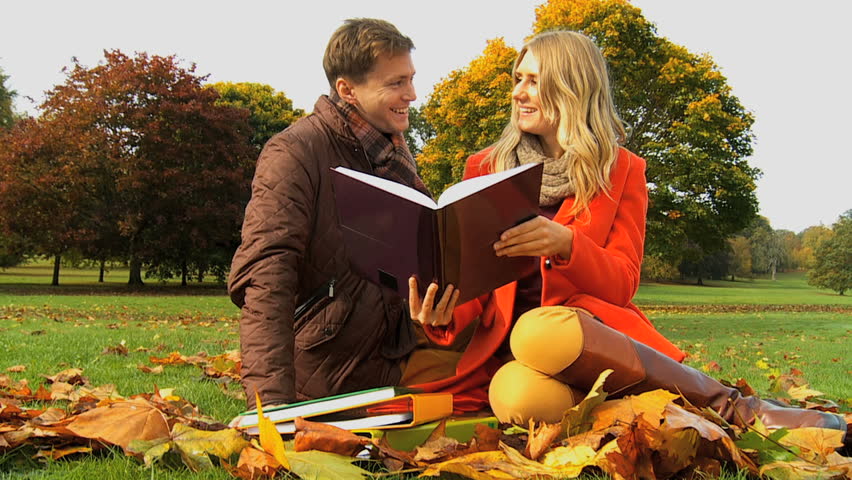 Caucasian students discussing college notes among country park Fall leaves