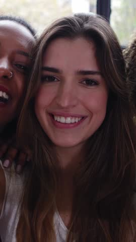 Vertical HD video of young happy group of multiracial female friends having fun taking video selfie together at home. Friendship and technology lifestyle concept