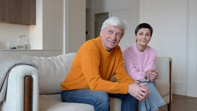 Delighted smiling senior married couple relaxing on couch in home, looking out window and talking, laughing, joking, dreaming. Emotional support and joy in family, romantic routine in retirement age - Powered by Shutterstock - Get 15% off with code: PIKWIZARD15