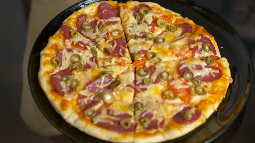 Hungry family hands take homemade pizza. A view of adults and child hands takes the sliced pizza from the plate because of hunger.