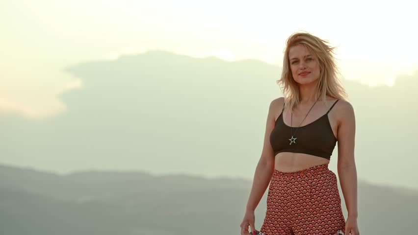 Woman Standing and Smiling on the Beach at Sunset