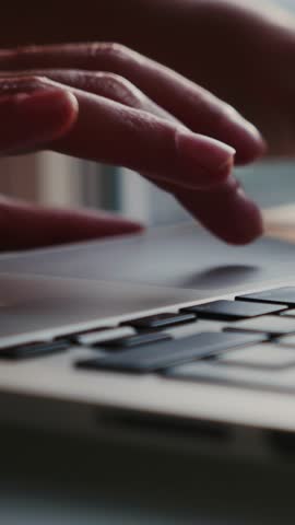 Female hands typing on laptop computer keyboard and using touch pad for searching in internet online, close up of hands. Business office concept. Vertical video