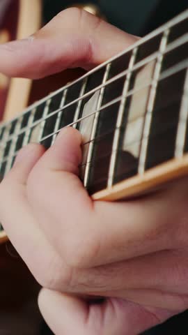 Man hand playing electric guitar, picking and strumming strings. Close up of male hand and guitar strings. Music concept. Vertical video
