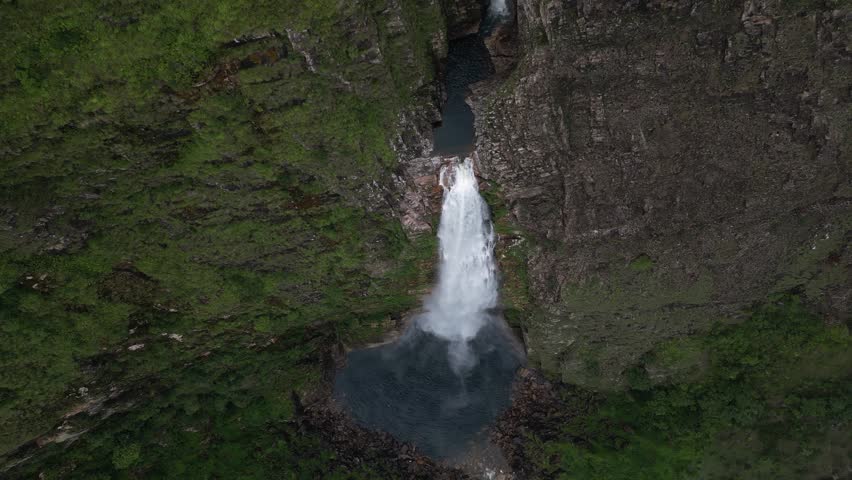 Rotating aerial descends toward tall Casca D'anta waterfall in Brazil