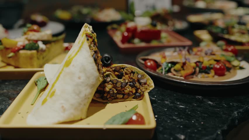 Close-up of a freshly made vegan burrito filled with rice, beans, and vibrant vegetables, served on a yellow plate. Delicious Vegan Burrito With Rice And Beans On Yellow Plate