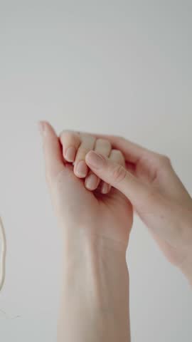 Close-up of hands with an elegant manicure, gently massaging each other, set against a clean, white background. The image conveys relaxation, self-care, and beauty.