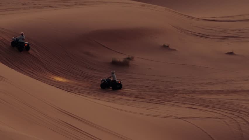 Four-wheelers ride through the Moroccan desert at sunset. Tourists enjoy a day of adventure on quad bikes on the sand dunes. A breathtaking aerial view of the vast desert landscape and thrill-seekers.