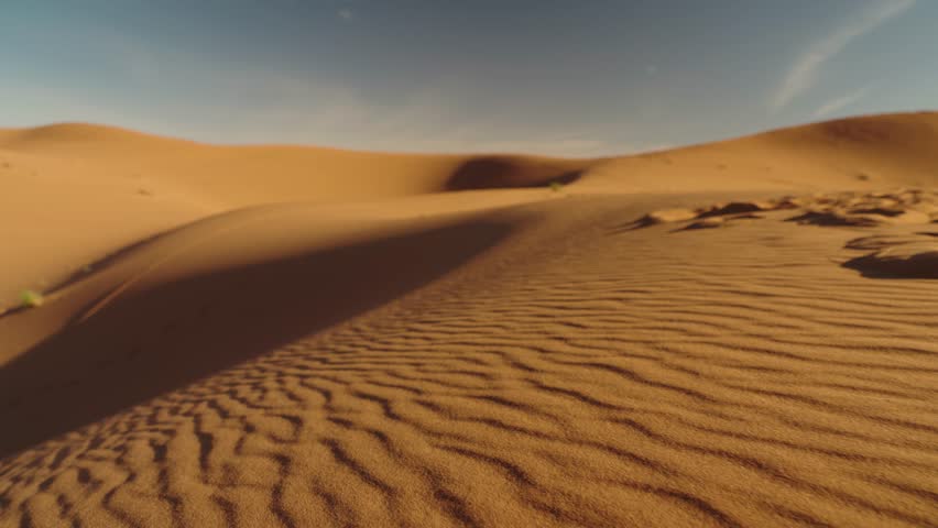 Scenic view of the rippling sand dunes in the Sahara Desert, Morocco. Sunlight casts shadows across the textured sand, creating a serene landscape. Perfect for travel, nature, or adventure projects.