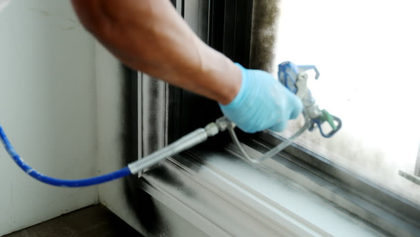 Painter painting the window in black color with spray machine. Handy painting. Wide shot 