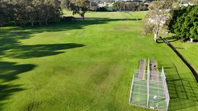 Aerial footage of cricket practice nets in a lush park setting, captured in bright daylight with clear skies - Powered by Shutterstock - Get 15% off with code: PIKWIZARD15