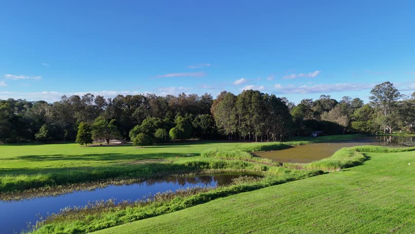 Drone footage captures lush greenery, wetlands, and a serene pond under clear blue skies in Gold Coast, Australia