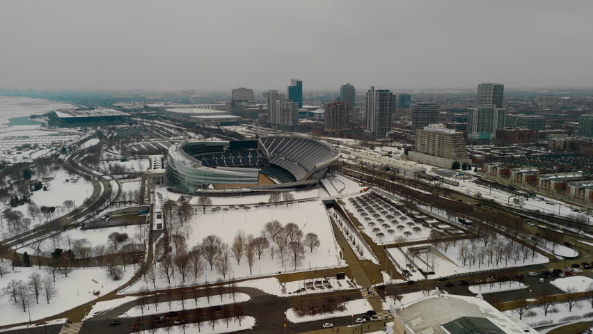 The aerial view of a snowy urban Soldier field in Chicago downtown . Towering buildings with Soldier field in the background. 