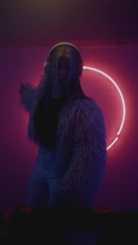 DJ woman dancing on night rave in neon club. Female disk jockey playing techno music set at party