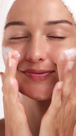 Happy Caucasian woman massages cleanser foam on face while smiling in a towel. High quality skincare and spa visual perfect for beauty, wellness, and facial care advertisements.