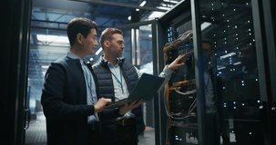 Asian IT Technician with a Laptop Computer and Caucasian Male Engineer Colleague are Talking in Data Center while Working Next to Server Racks. Running Diagnostics and Doing Maintenance Work - Powered by Shutterstock - Get 15% off with code: PIKWIZARD15