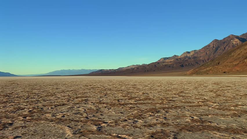 Expansive salt flat, jagged mountains and a clear blue sky in Death Valley National Park, California, USA