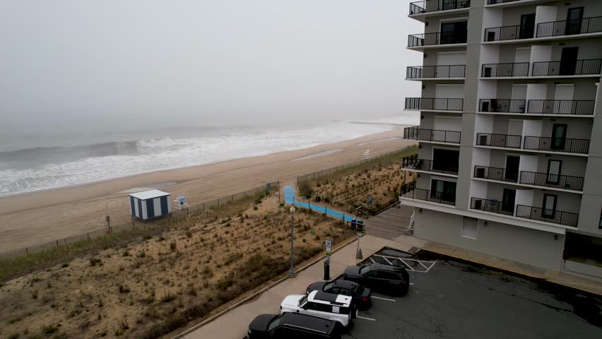 long descending drone shot down to foggy beach on a cloudy moody day in Delaware