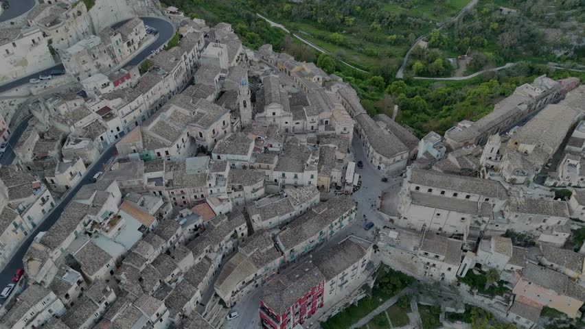 A drone flight horizontally on Ragusa city during sunset revealing the profile of the city on the hills