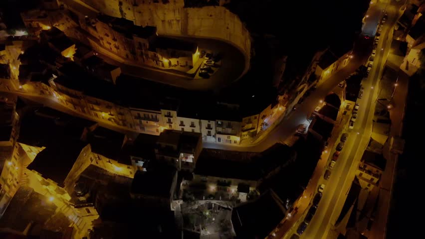 Night drone flight over curvy roads in Ragusa revealing the city